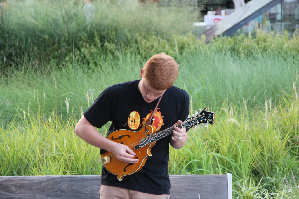 A young volunteer plucks at a mandolin in front of the Winspear Opera House downtown.