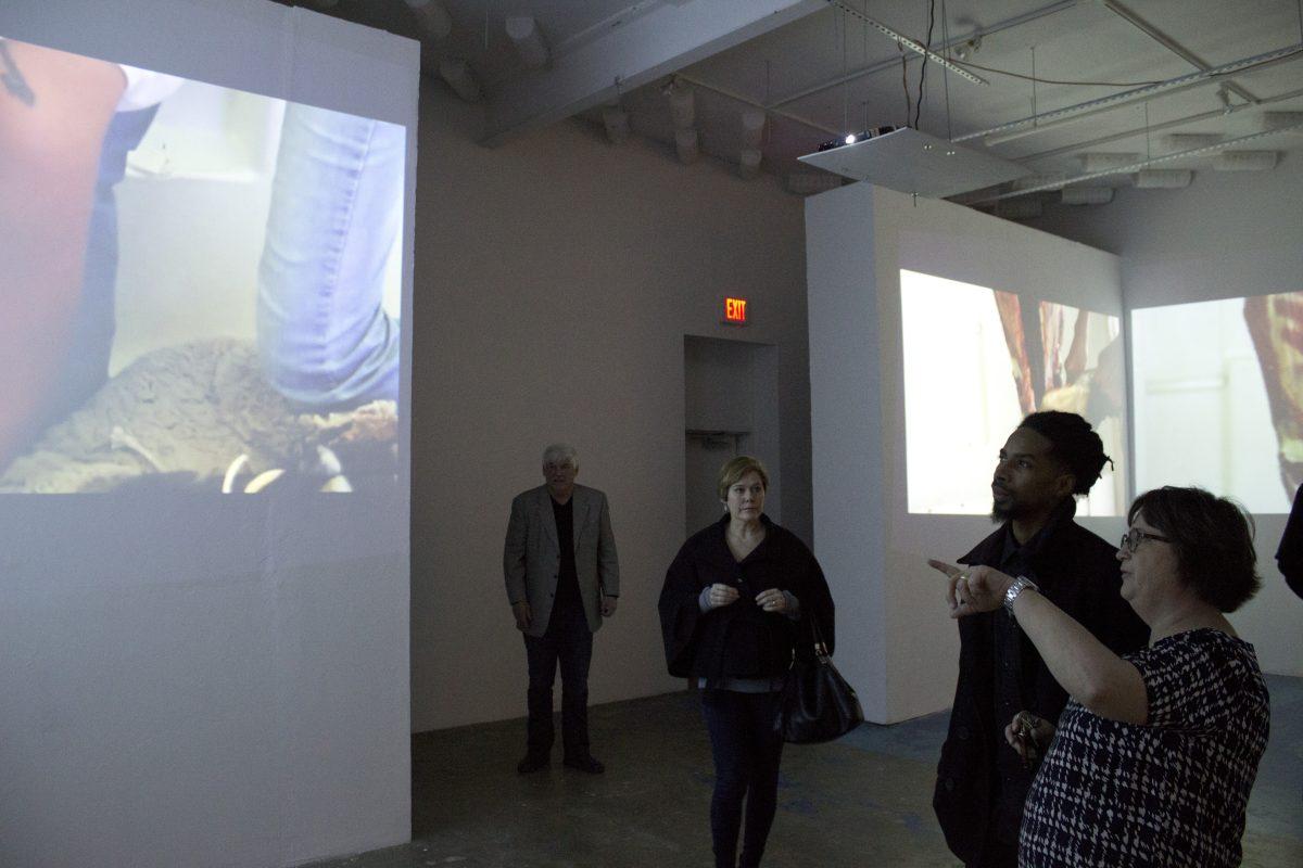 Marcelo Yates| Staff
Art showgoers observe the video installation created by Postcommodity, an internationally acclaimed Native American art collective who brought their exhibit to CentralTrak. The installation, titled “Gallup Motel Butchering,” will be showcased through Feb. 21.