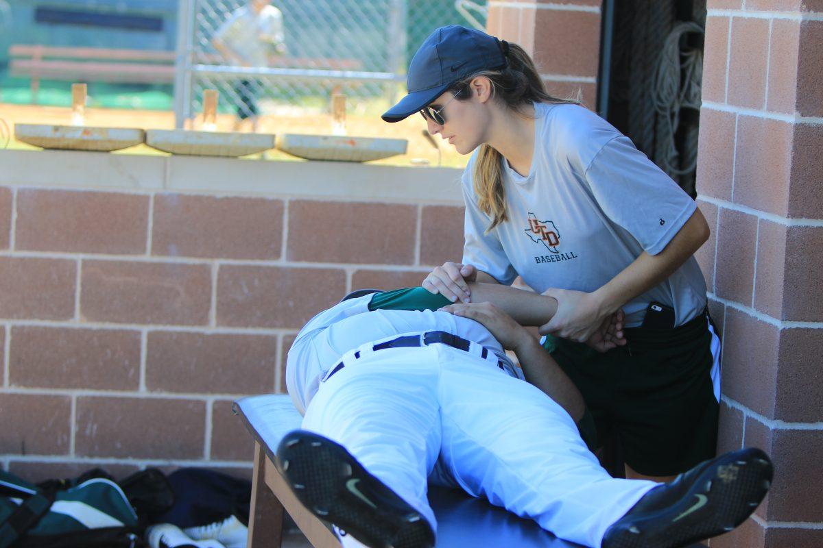 Kerri Kalina, one of the new assistant athletic trainers, works out an injury for a player on the baseball team. Kalina came to UTD from East Texas Baptist University, where she gained experience working with the head athletic trainer. Photo by Ankith Averineni | Mercury Staff.