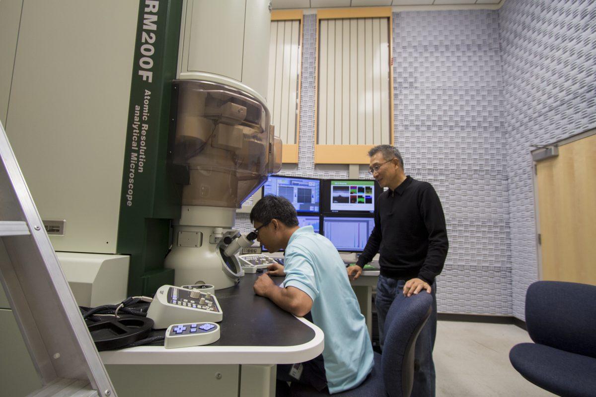 Qiaoxing Wang (left), a material sciences and engineering doctoral student, looks into an electron microscope in a lab in the Natural Science Engineering Research Laboratory. Wang was a key member of the team working on the transistor project. He worked under the supervision of Moon Kim, a distinguished professor in the same field. Photo by Chris Lin | Mercury Staff.