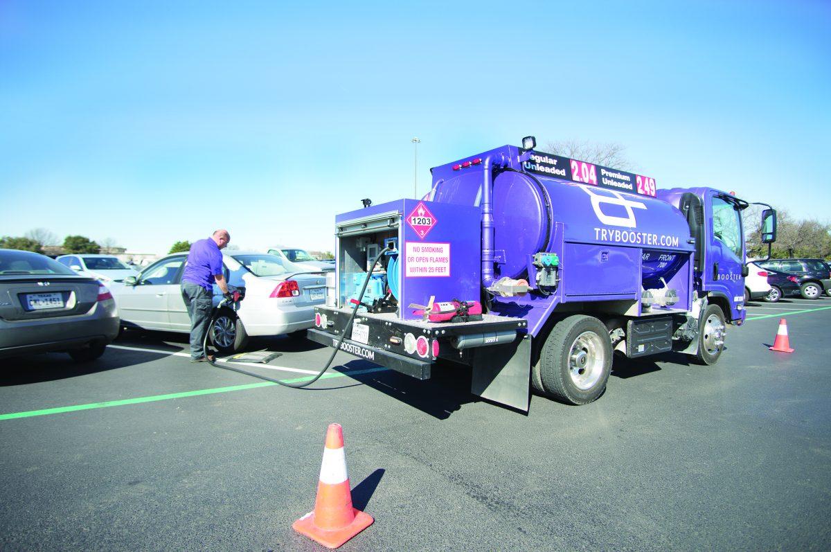 An employee at Booster Fuels fills a car with gas in Lot B. Students can use Booster Fuels by downloading the app and requesting service any weekday between 6 a.m. and 8 p.m. Ryan Leech, the campus representative from Booster Fuels said the company plans to expand its offerings to include windshield washes, tire shines and wiper replacements by mid-February. Photo by Minh Nguyen | Mercury Staff.