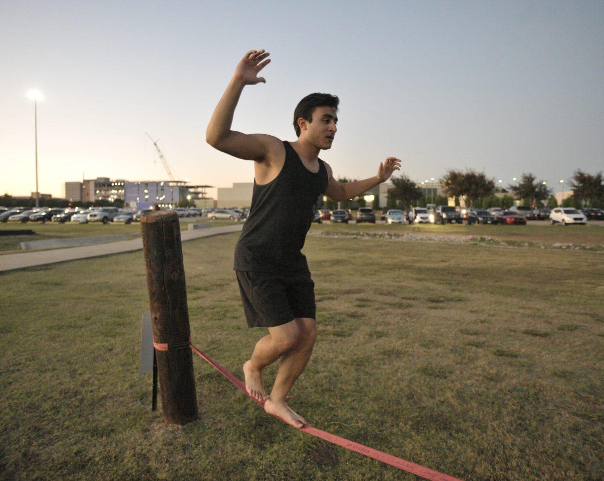 A student balances on a rope to practice slacklining by the UTD soccer fields as part of a clinic offered by University Recreation’s outdoor excursion program on Oct. 13. Photo by Ian Bird | Mercury Staff.