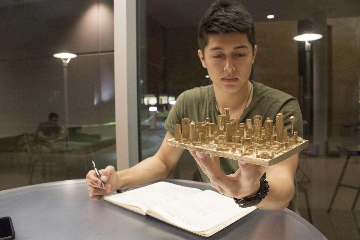 Gabe Villiani, information technology and systems junior and co-founder of Metro Blocks, studies a 3-D printed skyline of Dallas that his company created. Photo by William Legrone | Photo Editor.