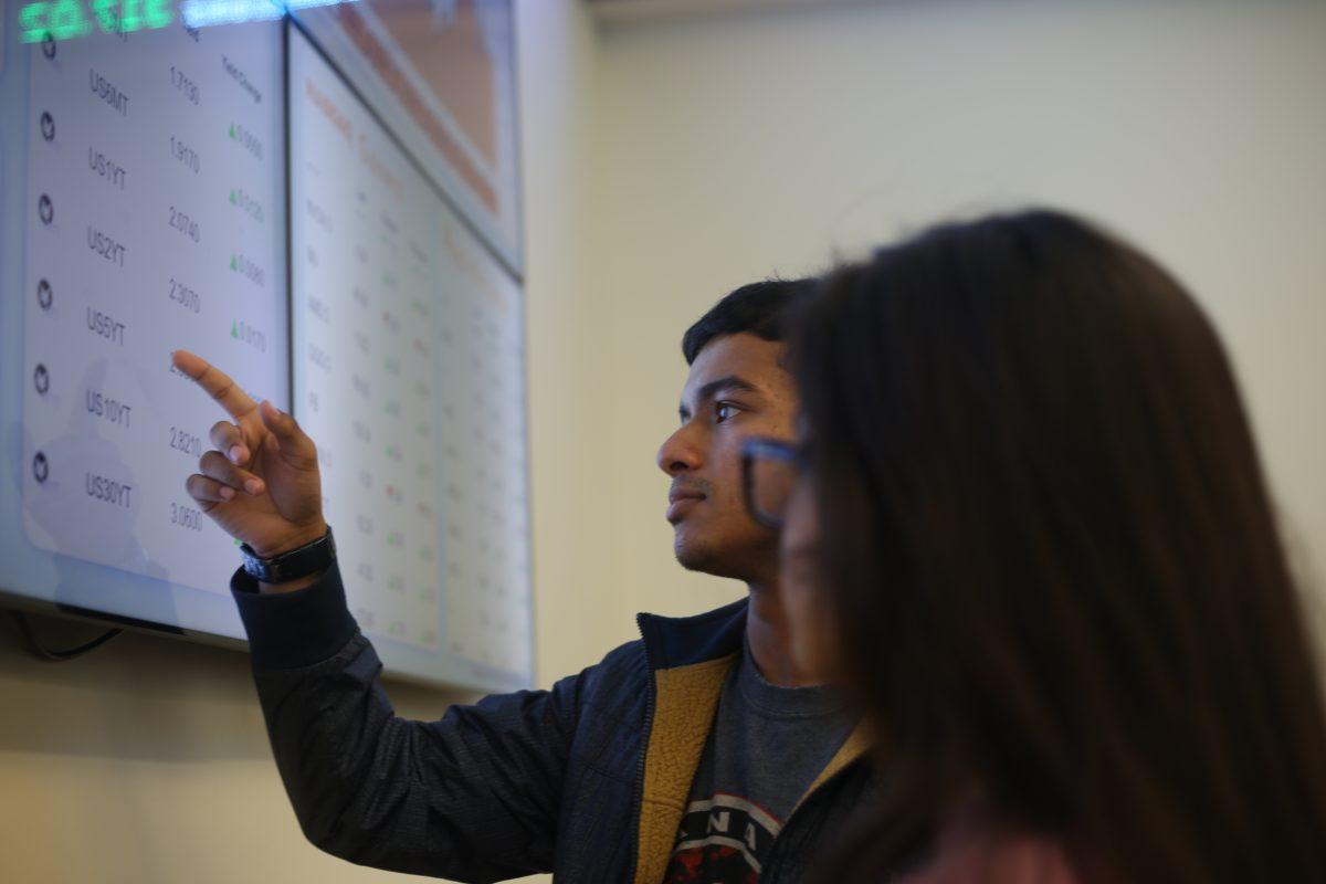 Vice President of the Texas Investment Group Adeeb Ahmed (left) and Director of Communications Faiza Zaman plan for investments in the the Naveen Jindal School of Management Finance Trading Lab on April 5. Photo by Noah Whitehead | Mercury Staff.
