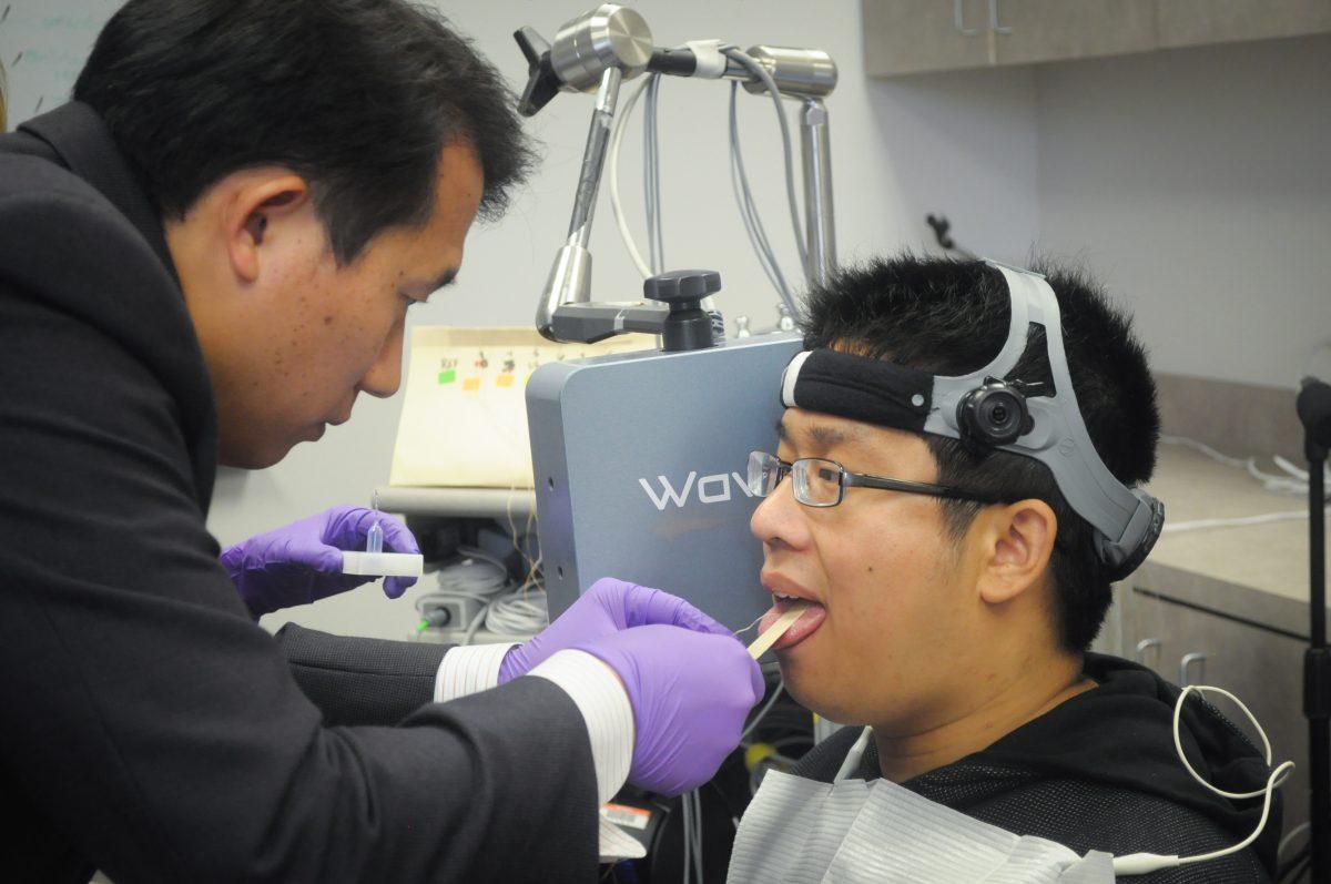 Bioengineering professor Jun Wang (left) attaches biosensors to research assistant Beiming Cao to track the movement of his speech. Photo by Madeline Ambrose | Mercury Staff.