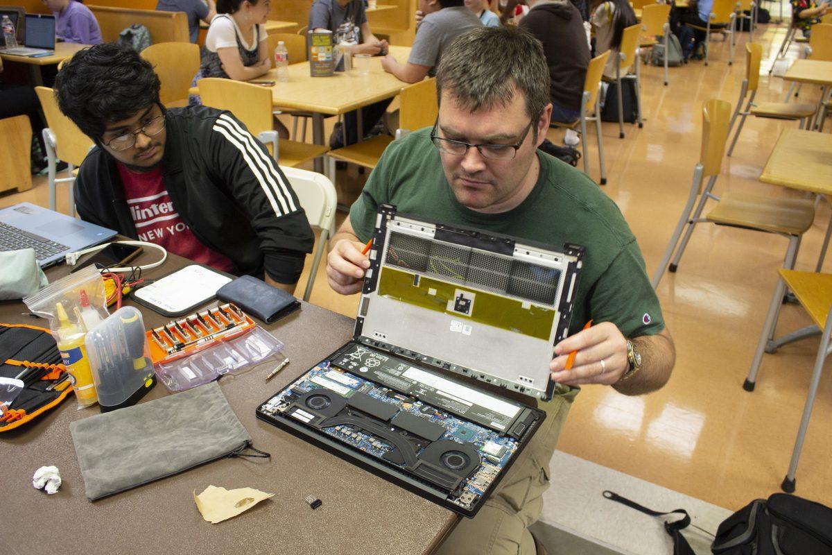UTD alumnus Joseph Vtlen opens up a laptop to take out the battery in the Student Union as part of “Fix-It-Friday.” Photo by Emaan Bangash | Mercury Staff.