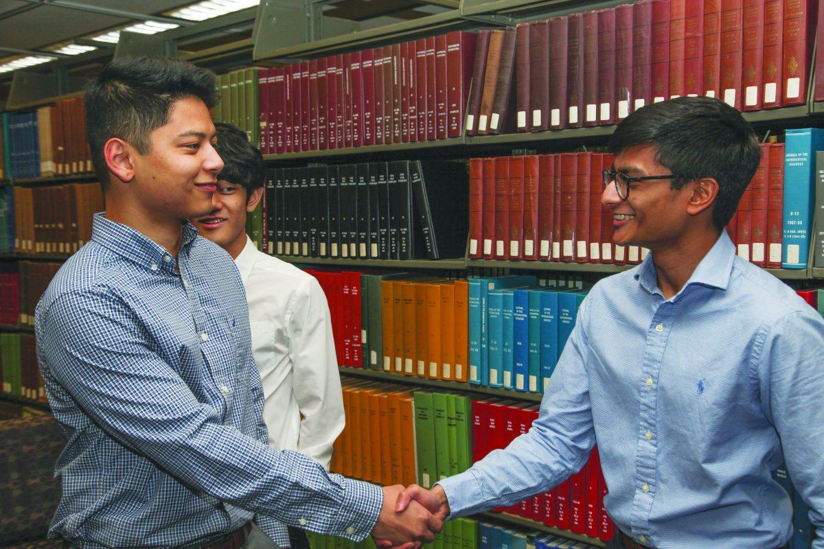 Economics graduate student Adarsha Piya and computer science senior Santhosh Paramasivan shake hands during a 180 Degrees Consulting meeting. Photo by Pavan Tauh | Mercury Staff.