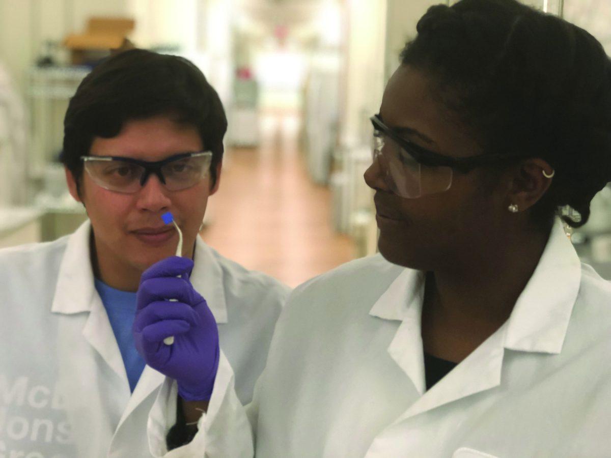 Chemistry Ph.D. student Michael Luzuriaga and a colleague look at one of their 3D-printed microneedles. The researchers hope to use the patches as an alternative to common drug delivery methods such as vaccines. Courtesy of Michael Luzuriaga