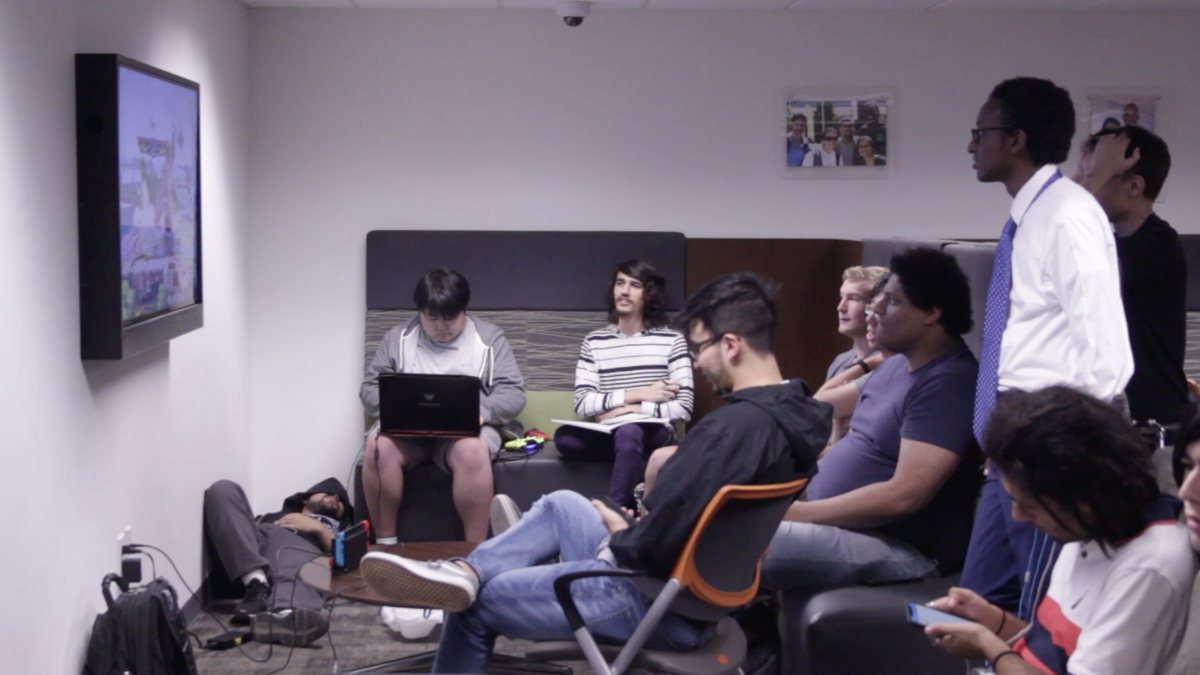 A group of students gather around on of three TVs to play “Super Smash Bros” together in the game room on the first floor of the Student Union.   Photo by Ryan Magee | Video Editor