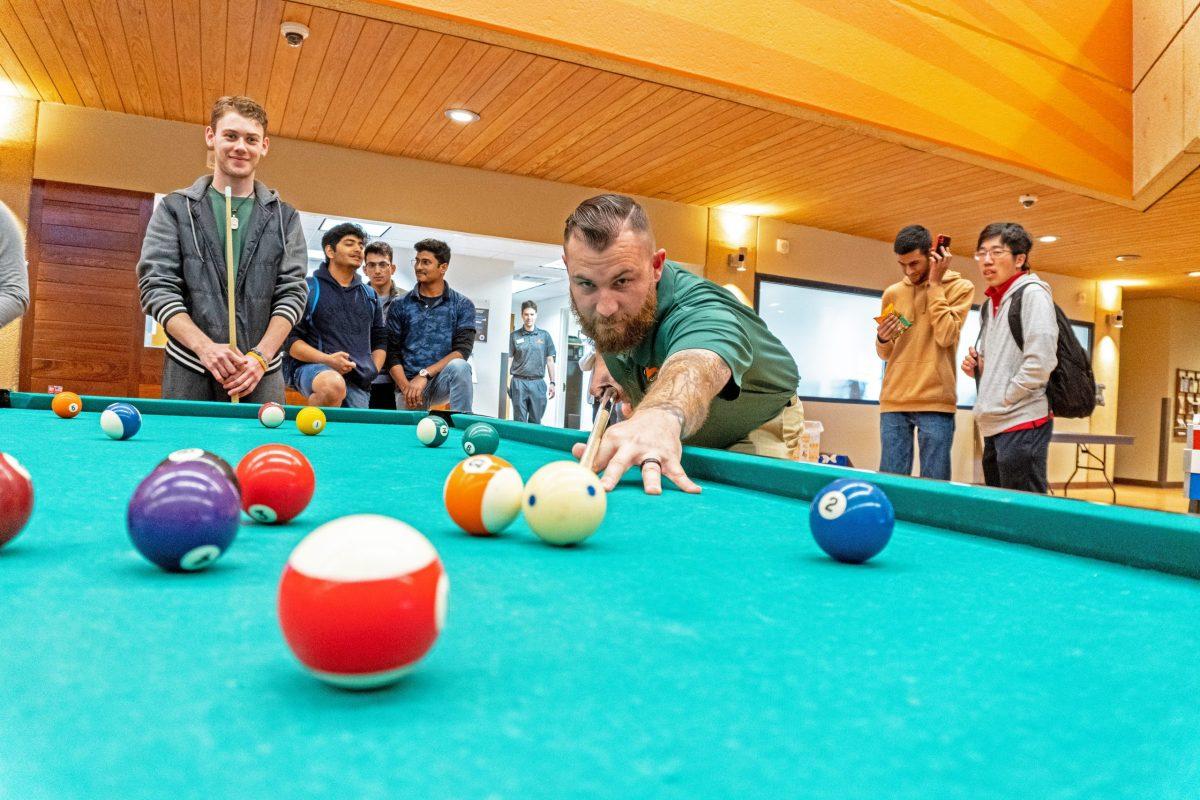 Criminology junior Jeremiah Kincaid (center) serves as president of the billiards team, which recently saw members place at a UT Arlington tournament. Photo by Grace Chang | Mercury Staff