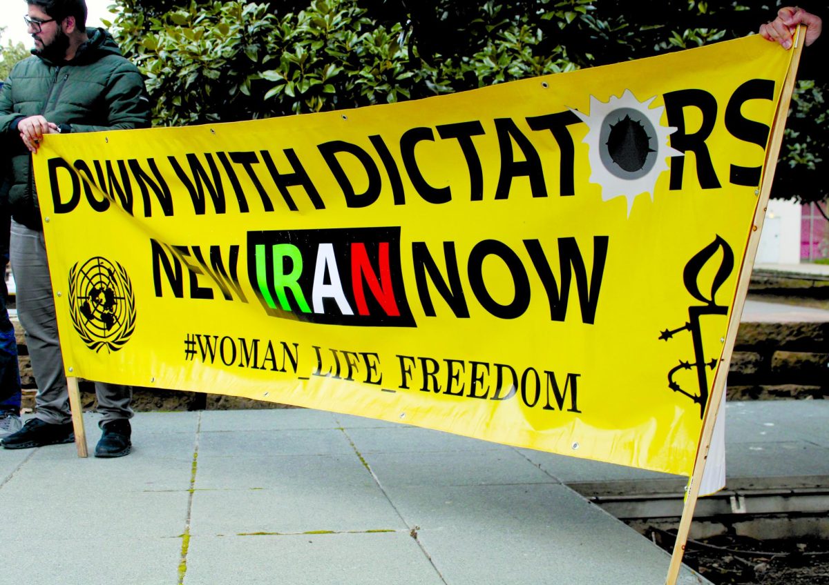 Demonstrators hold a banner reading _Down with Dictators. New Iran now_ during a protest at Chess Plaza.