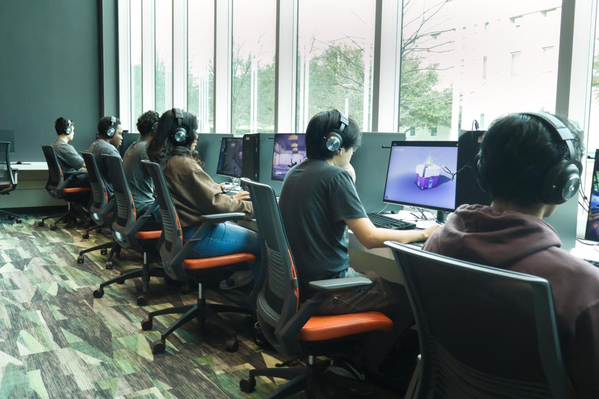  Students play video games at Comets LANding in front of a window overlooking campus.