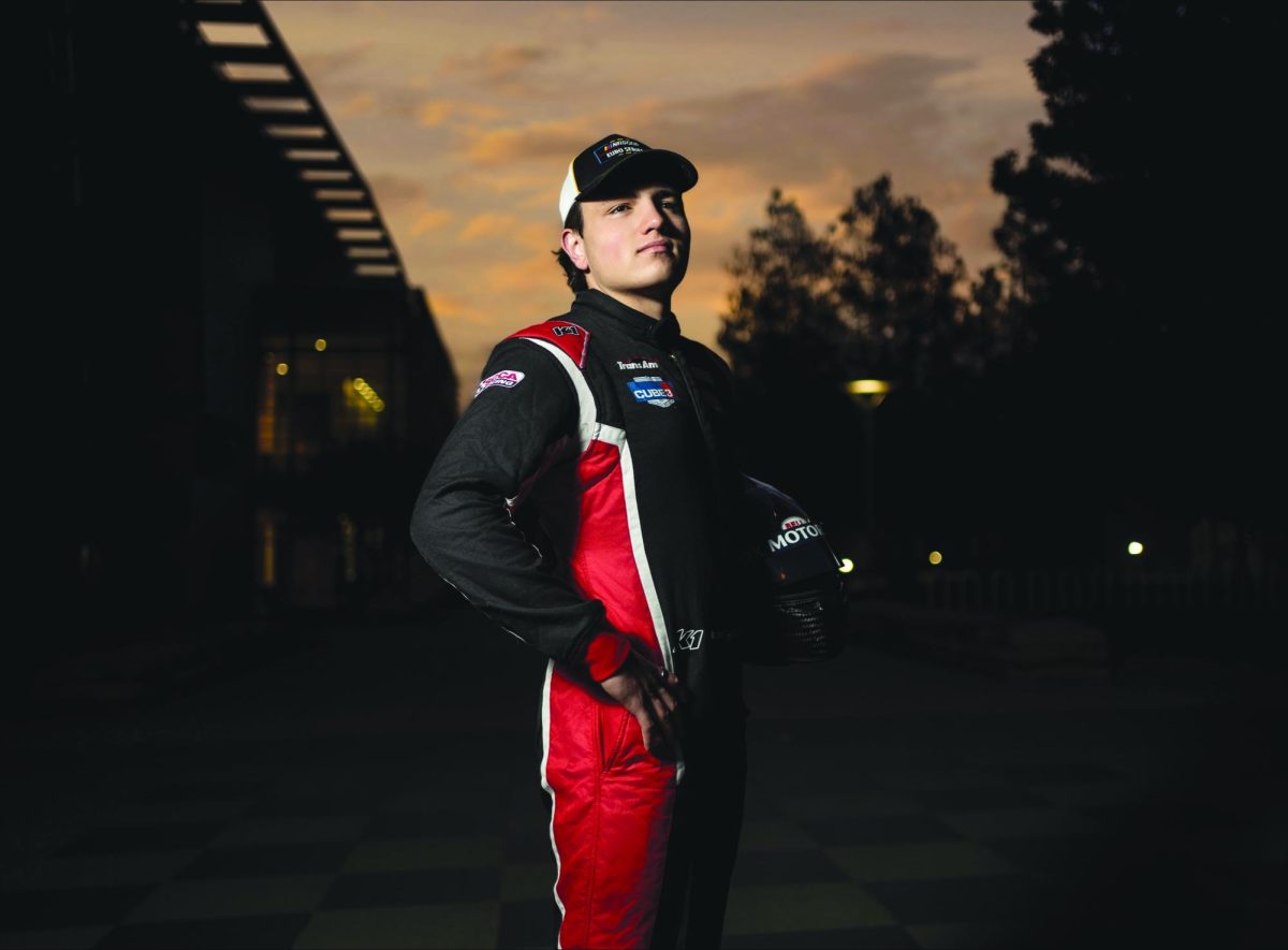 Vinnie Meskelis stands in front of the sunset, decked out in racing gear